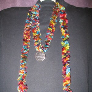 May include: A long, colorful, fringed necklace with a silver pendant that reads "I can do everything through Him who gives me strength".