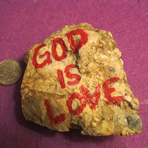 May include: A rock with the words "God is Love" painted in red on it.