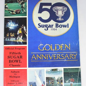 May include: A vintage Sugar Bowl program cover, featuring a blue background with a large "50" and a trophy, marking the Golden Anniversary. The cover includes game action photos and details for the Auburn vs. Michigan game on January 2, 1984.