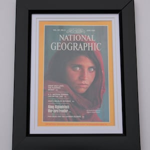 May include: A vintage National Geographic magazine cover from June 1985 featuring a young Afghan girl wearing a red headscarf. The cover text reads "Along Afghanistan's War-torn Frontier".