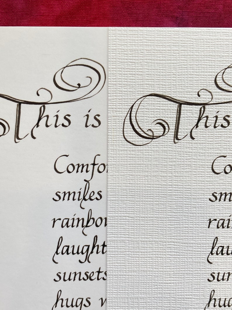May include: A close-up of a handwritten note that reads "This is comfort, smiles, rainbows, laughter, sunsets, hugs and..." The note is written in black ink on white paper with a textured surface.