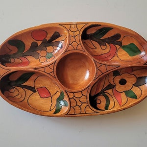 May include: Wooden serving tray with five compartments, featuring hand-painted floral designs in red, green, and black. The oval tray has a central round section and is ideal for serving snacks or appetizers.