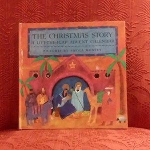 May include: A children's book titled "The Christmas Story: A Lift-the-Flap Advent Calendar" with illustrations of the Nativity scene. The book is set against a red patterned background. The cover features a star, palm trees, and figures.