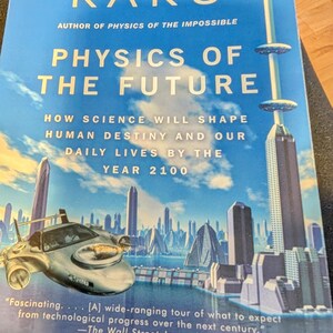 May include: A book titled "Physics of the Future" by Michio Kaku. The cover features a futuristic cityscape with flying vehicles and tall buildings. The text includes quotes from The Wall Street Journal.