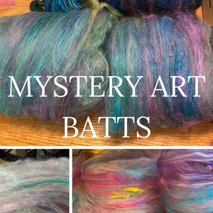 May include: A close-up of colorful, fluffy yarn batts in shades of blue, purple, pink, and green. The yarn is arranged in a pile and labeled "MYSTERY ART BATTS".