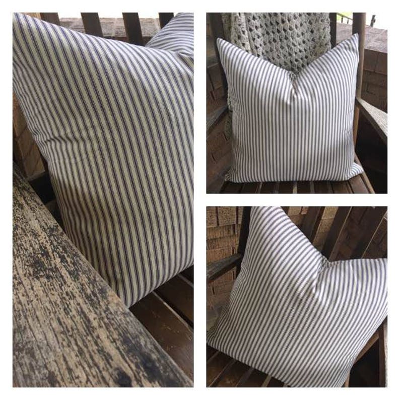 May include: Three striped pillows with a white background and thin navy blue stripes. The pillows are shown on a wooden chair and a wooden bench.