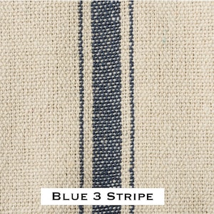 May include: Close-up of a natural linen fabric with three blue stripes. The fabric has a woven texture and is a light beige color. The stripes are a dark blue color and are evenly spaced. The text "BLUE 3 STRIPE" is printed at the bottom of the image.
