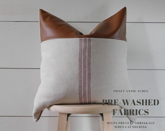 May include: A brown leather and cream linen pillow with red stripes. The pillow is sitting on a wooden stool. The text "Sweet Annie Acres Pre-Washed Fabrics Helps Prevent Shrinkage When Laundering" is printed on the background.