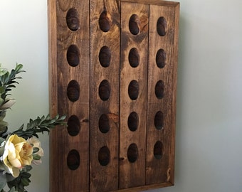 May include: A wooden wall-mounted wine rack with a dark brown stain. The rack has 20 slots for wine bottles.