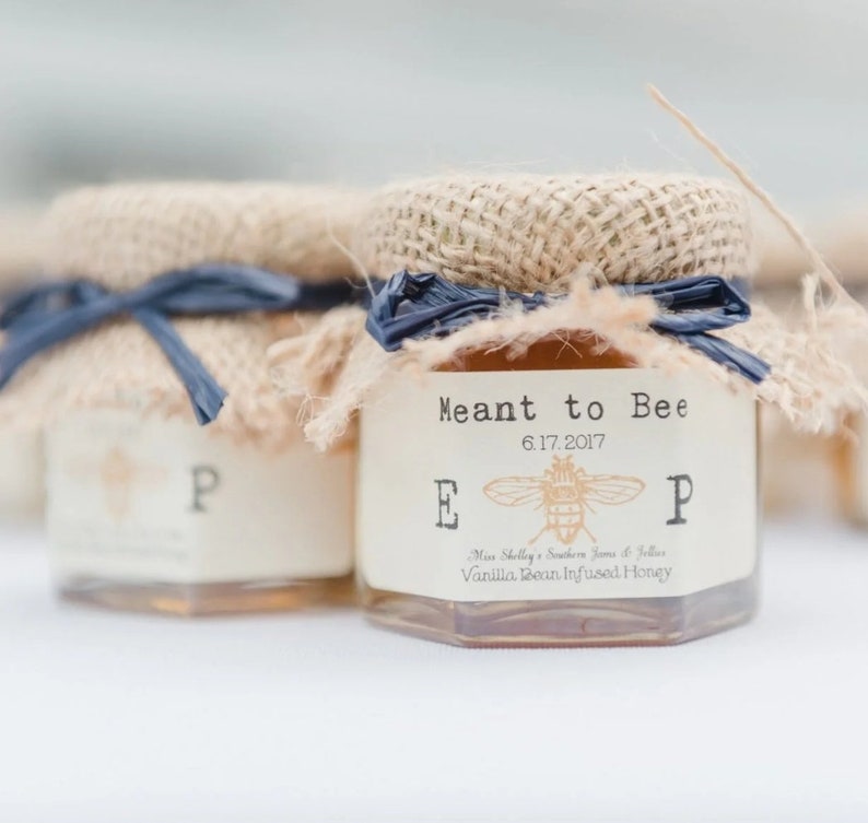 1.5oz hexagon honey favor featured in Southern Living magazine. The topper is a Natural Burlap with a Pearl Navy Raffia Ribbon. The label is in Ivory and our Vintage Bee Monogram Initial Design (font is in a Vintage Typewriter style.)