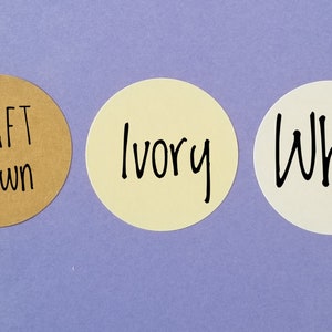 May include: Three round paper stickers with different colors and text. The first sticker is brown with the text "KRAFT Brown". The second sticker is ivory with the text "Ivory". The third sticker is white with the text "White".