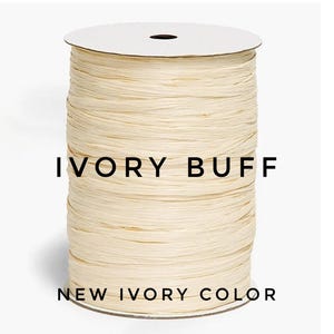 May include: A spool of ivory buff colored ribbon with a textured, fibrous appearance. The spool is cylindrical with a white top and bottom disc. The text IVORY BUFF and NEW IVORY COLOR is printed in black across the center of the ribbon spool.