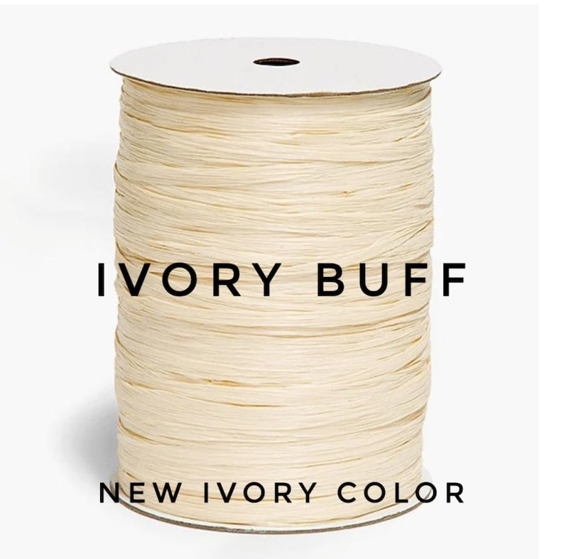 May include: A spool of ivory buff colored ribbon with a textured, fibrous appearance. The spool is cylindrical with a white top and bottom disc. The text IVORY BUFF and NEW IVORY COLOR is printed in black across the center of the ribbon spool.