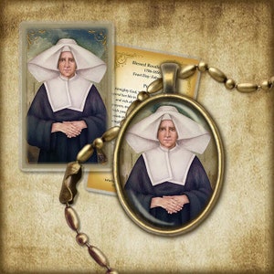 May include: A gold-toned oval pendant with a glass insert featuring a painting of a woman in a white habit and a white head covering. The pendant is on a gold chain. The text on the card reads "Blessed Rosalie 1786-1856 Feast Day: Feb Almighty God, ..."