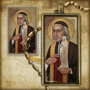 May include: A religious pendant featuring a colorful image of a man in a priest's robe holding a small statue of a woman. The pendant is framed in a gold-colored metal.