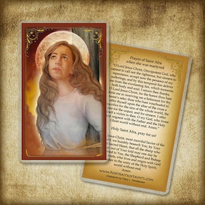 May include: A prayer card featuring a painting of Saint Afra, a Christian martyr. The card has a red border and includes a prayer to Saint Afra. The text on the card reads "Prayer of Saint Afra when she was martyred" and "Holy Saint Afra, pray for us!"