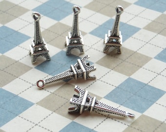 May include: Five silver Eiffel Tower charms, each with a detailed design. The charms are arranged on a checkered background.