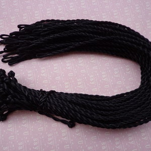May include: A bundle of black twisted cord, approximately 50 pieces, with a loop at one end. The cord is about 1/4 inch thick and is ideal for crafts, jewelry making, and other projects.