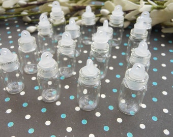 Puede incluir: Una colección de 15 botellas de vidrio transparente con tapas blancas de rosca y un pequeño lazo en la parte superior. Las botellas están dispuestas sobre una superficie de lunares negros y blancos.