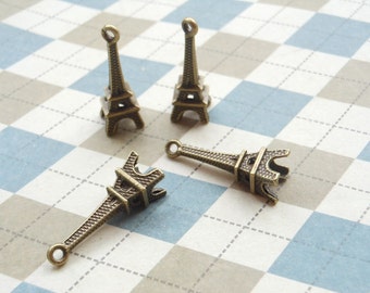 Peut inclure: Quatre breloques Tour Eiffel en or antique. Les breloques sont petites et détaillées, avec un design délicat. Elles sont parfaites pour ajouter une touche de charme parisien à vos bijoux ou à vos créations.