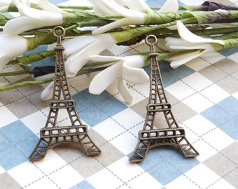 Puede incluir: Dos encantos de la Torre Eiffel de color dorado antiguo. Los encantos son detallados e intrincados, con un diseño delicado.