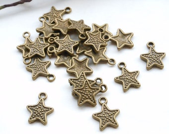 Peut inclure: Un tas de breloques en forme d'étoile en bronze antique avec une boucle pour accrocher. Les breloques ont une surface texturée et sont parfaites pour la fabrication de bijoux ou l'artisanat.