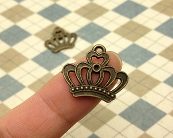 May include: Two antique gold-toned metal crown charms. The crown charms have a detailed design with a heart shape at the top and a beaded border.