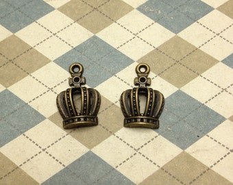 May include: Two antique gold-toned crown charms with a detailed design. The charms have a loop at the top for attaching to jewelry or other crafts.