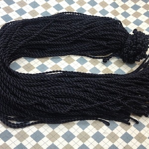 May include: A bundle of black twisted cord with a tassel at the end. The cord is approximately 1.5 inches wide and is made of a soft, pliable material.