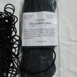 May include: Black nylon braided cord in a clear plastic package. The label reads "Nylon Braided Cord" and "100 ft." The cord is described as light weight, strong, durable, and quick drying. Made in the USA.