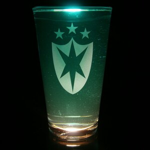Peut inclure: Un verre transparent avec un liquide vert et un bouclier blanc avec une étoile et quatre étoiles au-dessus.