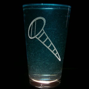 以下が含まれることがあります： 青い色合いの透明なガラスに、白い釘の絵がエッチングされています。ガラスは透明な液体で満たされています。