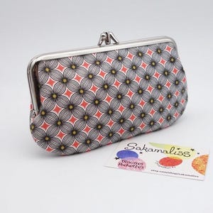 Cartera con cierre metálico con separación central, 2 compartimentos y tres bolsillos, estampados geométricos, naranja, amarillo y negro