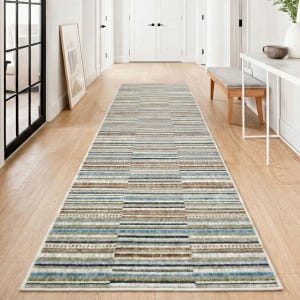 May include: A long, rectangular hallway rug with a striped pattern in shades of blue, brown, and cream. The rug's design features horizontal stripes of varying widths, creating a textured appearance. The rug is placed on a light-colored wooden floor.