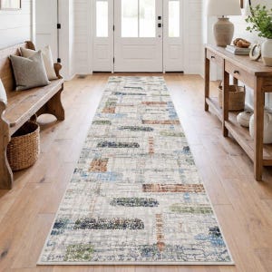 May include: A rectangular hallway rug with a cream background and a pattern of rectangular shapes in blue, green, and brown. The rug is placed on a wooden floor in a well-lit hallway.