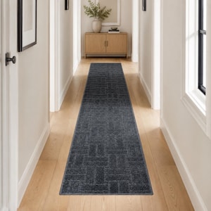 May include: A long, rectangular runner rug in a deep charcoal gray color. The rug features a repeating geometric pattern composed of small, textured rectangular blocks arranged in a basketweave style, covering the entire surface of the floor covering.