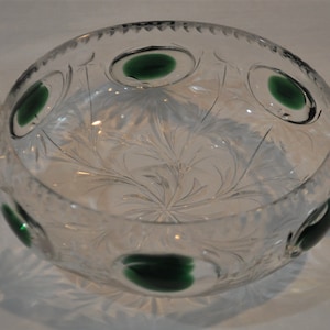 May include: A clear glass bowl with two handles and a cut glass design. The bowl has green accents around the rim.