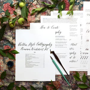 May include: A Kaitlin Style Calligraphy Premium Worksheet Set featuring instructional pages with black text, an index, and practice drills. Two calligraphy dip pens with dark brown and light teal handles rest on the paper near a small ink pot.