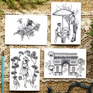 May include: Four black and white ink illustrations on white paper. One shows a French flag with a fleur-de-lis and flowers. Another depicts a cafe scene with a server and patron. A third shows a person walking through trees. The fourth features the Arc de Triomphe with roses.