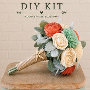 May include: A DIY kit for wood bridal blossoms featuring a bouquet of artificial flowers in shades of orange, cream, and mint green, accented with grey-green leaves and a jute-wrapped handle decorated with a small beige starfish ornament.