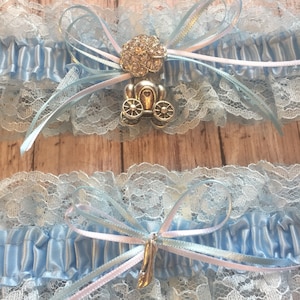 May include: Two blue and white lace garters with satin ribbon bows and a silver charm of a carriage with rhinestones.