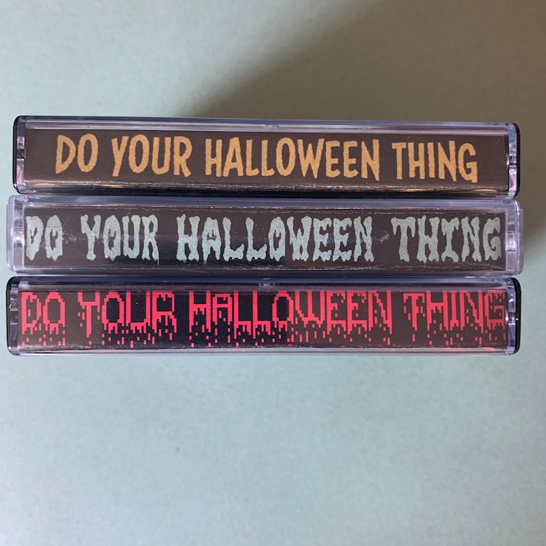 May include: Three cassette tapes with the text "Do Your Halloween Thing" printed on them. The top tape has yellow text, the middle tape has green text, and the bottom tape has red text.