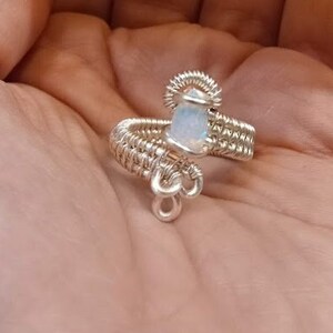 May include: A silver wire wrapped ring with a white opal gemstone.