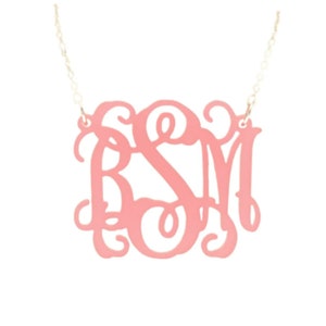 May include: A pink monogram necklace with the letters "BSM" in a cursive script font.