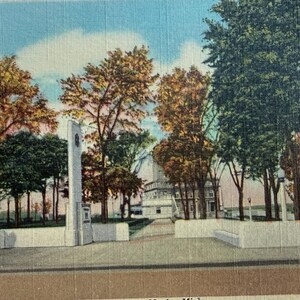 May include: Vintage postcard featuring the entrance to the Famous Soo Lock in Sault Ste. Marie, Michigan. The image shows a view of the entrance with trees and a building in the background. The sky is blue with clouds. Text on the bottom reads "Entrance to the Famous Soo Lock, Sault Ste. Marie, Mich."