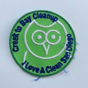 May include: Green circular patch with a white owl and the text "Creek to Bay Cleanup I Love A Clean San Diego" in blue.