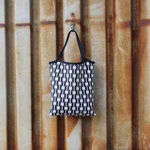 Peut inclure: Un sac fourre-tout noir et blanc avec un motif géométrique suspendu à un crochet sur un mur en métal rouillé.