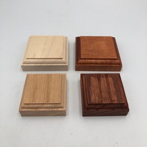 Puede incluir: Cuatro bloques cuadrados de madera, cada uno con una mancha de madera diferente. Los bloques están dispuestos en una cuadrícula de dos por dos. El bloque superior izquierdo es una mancha de madera clara, el bloque superior derecho es una mancha marrón rojiza, el bloque inferior izquierdo es una mancha marrón media y el bloque inferior derecho es una mancha marrón oscura.