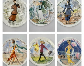 Puede incluir: Un juego de seis platos decorativos redondos de cerámica, cada uno con una ilustración pintada a mano de una persona con moda histórica. Los platos incluyen etiquetas de texto como Colette, La Belle Epoque, Edith, Daisy, Francoise y Martine et Vany.