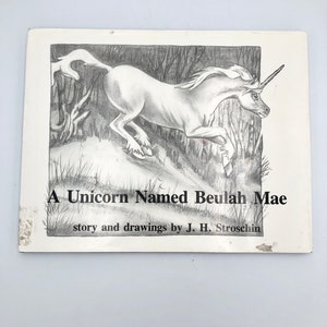 May include: A black and white illustration of a unicorn running through a forest. The title of the book is "A Unicorn Named Beulah Mae" and the author is J. H. Stroschin.